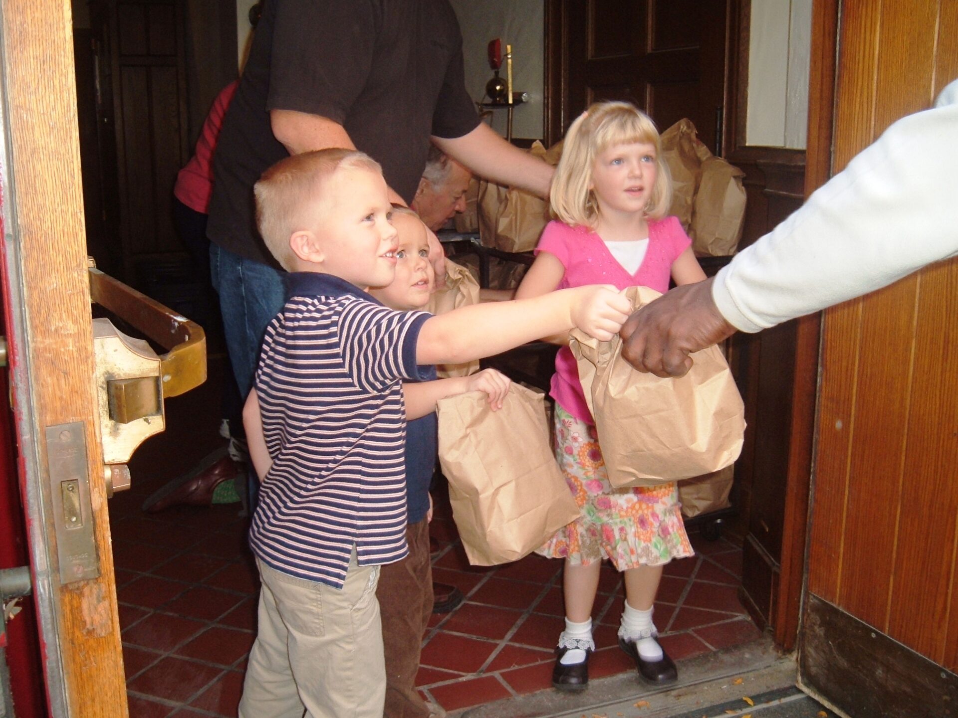 A group of kids holding onto brown bags