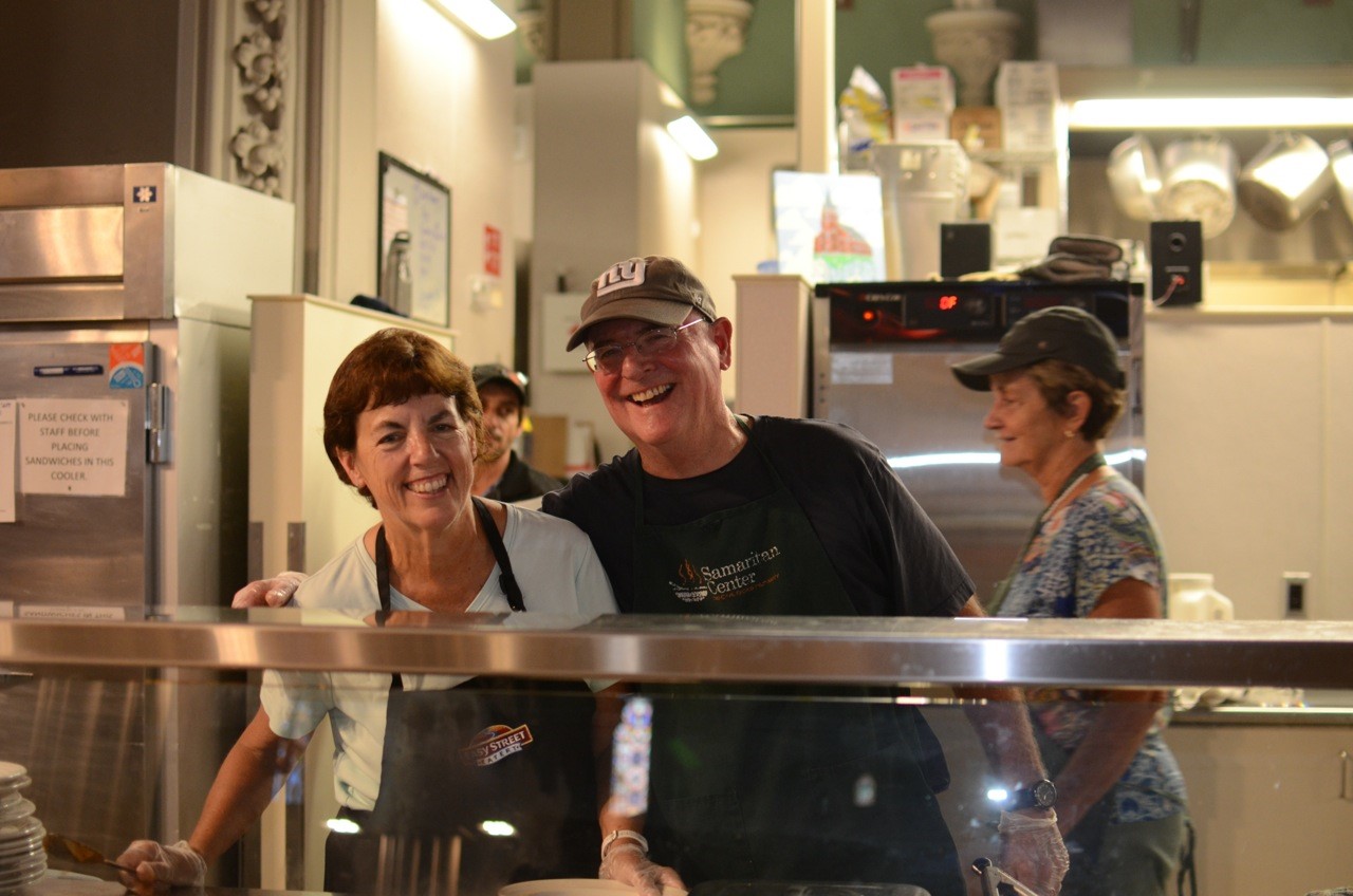 A man and woman smile for the camera while standing in front of an oven.