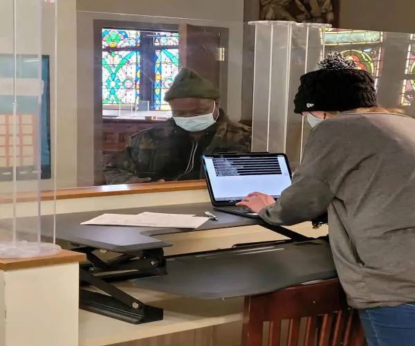 A man wearing a mask is using his laptop