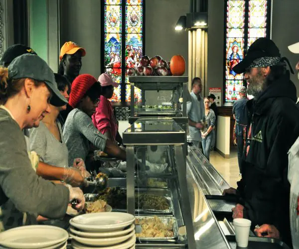 A group of people standing around a buffet line.