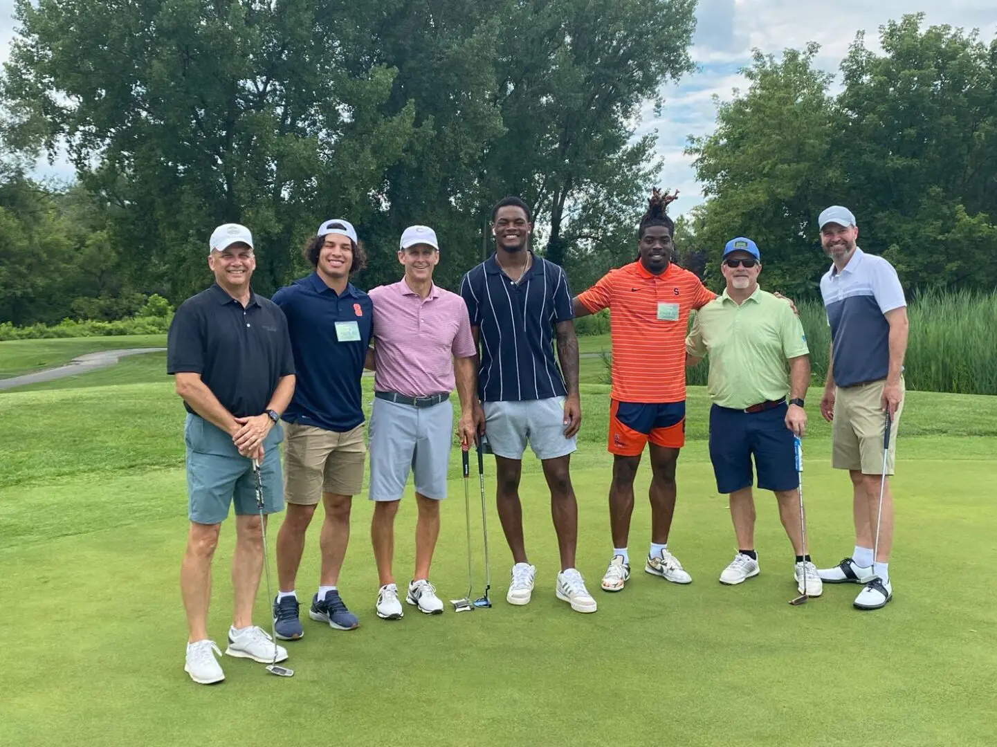 SU Football players stand with Soup Bowl Open committee chair PEter Derrenbacker and teammates on the course.