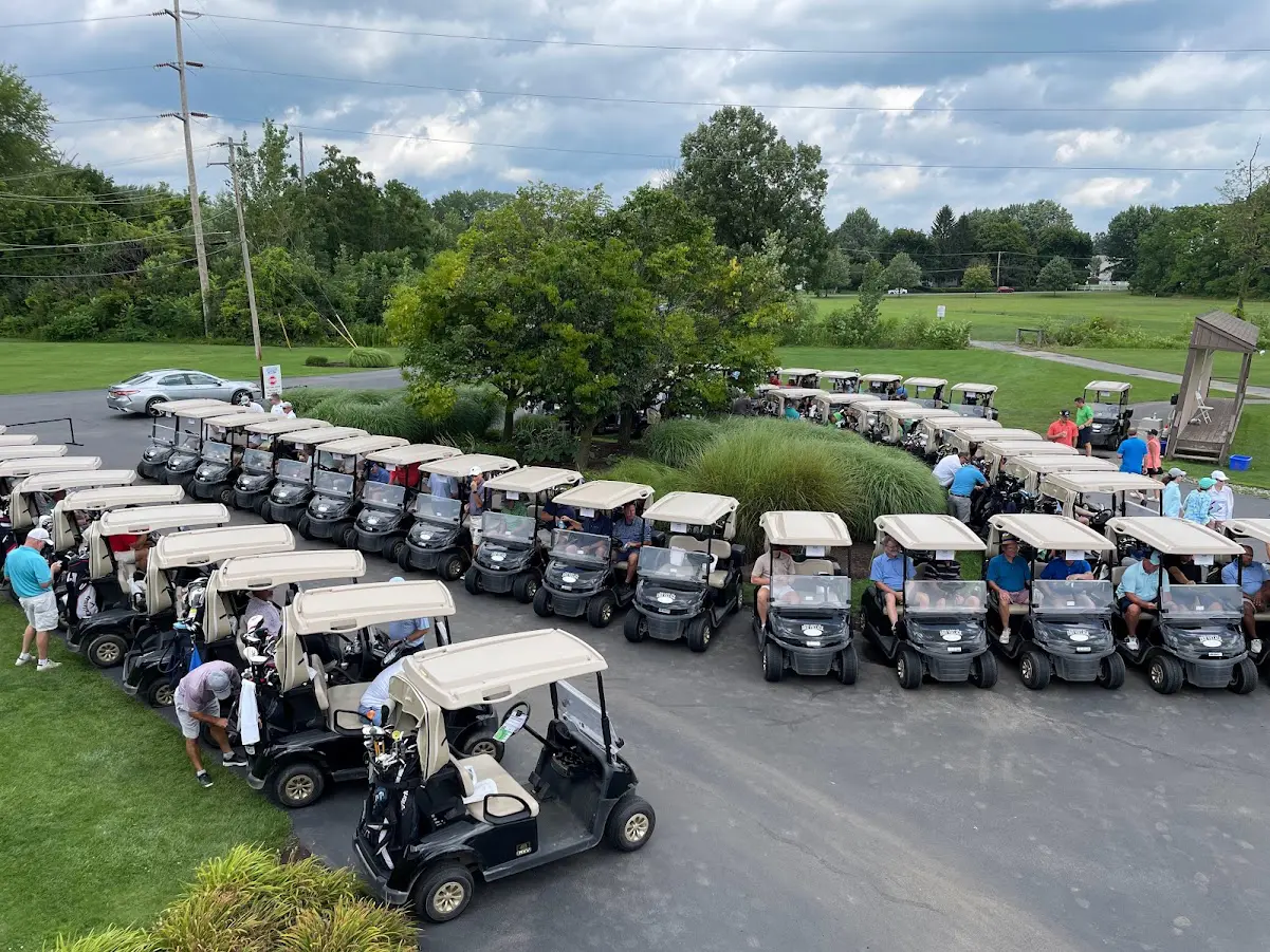 Participants in the 2023 Soup Bowl Open prepare to head out for the tournament: rows of golf carts with golfers in them circle the driveway.