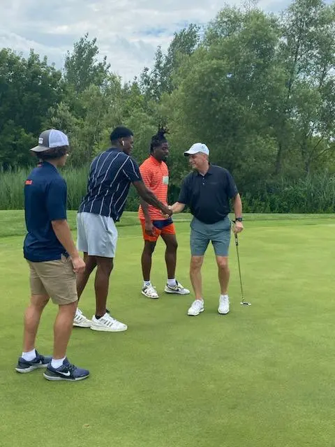 SU Football players meet golfers on the course.